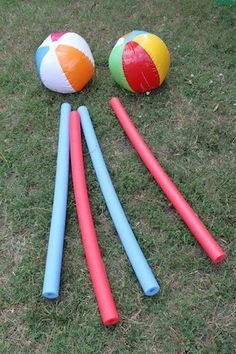 four beach balls and five plastic poles laying on the grass