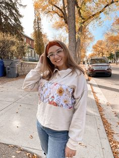 a woman standing on the sidewalk with her hands in her hair and wearing glasses, smiling