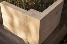 a wooden planter box sitting on top of a wooden fence next to some bushes