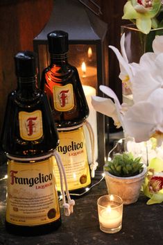 two bottles of tequila next to a candle and some flowers