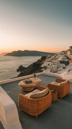 two wicker chairs sitting on top of a roof next to a body of water