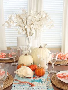 the table is set with pumpkins and white flowers