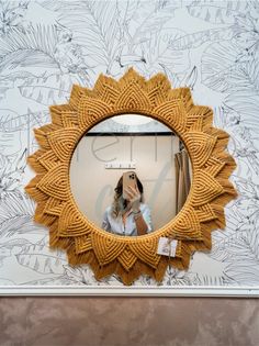 a woman taking a selfie in front of a mirror with an intricate design on it