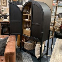 two black cupboards with wine glasses and baskets on them in a living room area