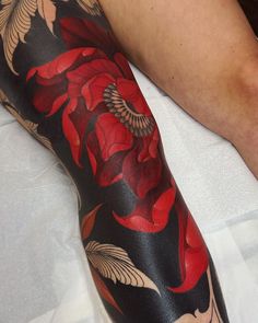 a person with a flower tattoo on their arm and leg is laying down in bed