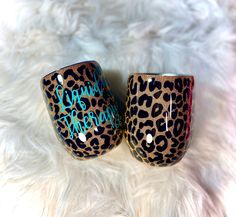 two leopard print cups sitting on top of a white fur covered floor