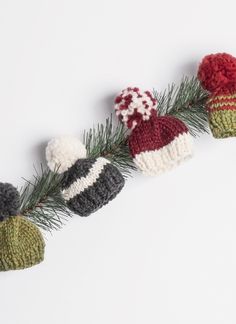 three knitted hats sitting on top of a pine branch