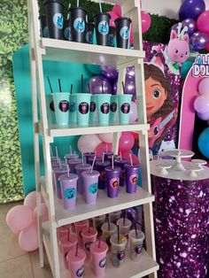 there is a shelf with cups and balloons on it in front of a birthday party backdrop