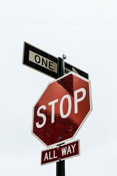 the stop sign has two street signs above it that read one way and all way