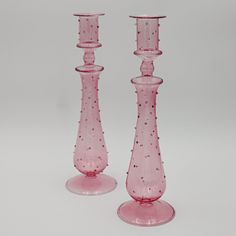 two pink glass candlesticks sitting next to each other