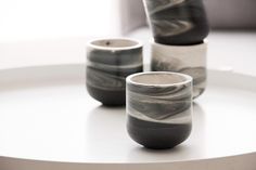 three marbled cups sitting on top of a white table next to each other in front of a window