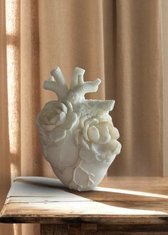 a heart shaped vase sitting on top of a wooden table