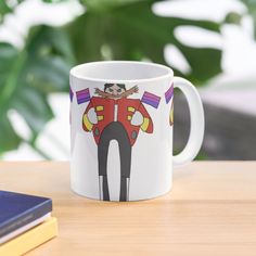 a coffee mug with an image of a cartoon character on the front and side, sitting on a table next to a book