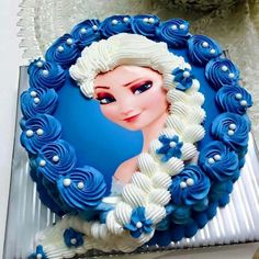 a frozen princess cake with blue icing and white frosting flowers on the top