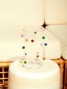 a glass sitting on top of a table next to a white couch with beads hanging from it