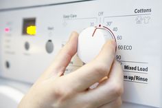 a person is pressing buttons on a dryer's control panel with the help of an appliance