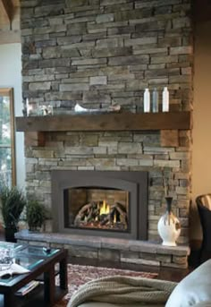 a living room filled with furniture and a fire place in the middle of a stone fireplace