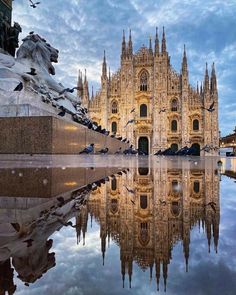 a large cathedral with many spires is reflected in the water