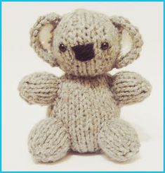 a small knitted teddy bear sitting up against a white background