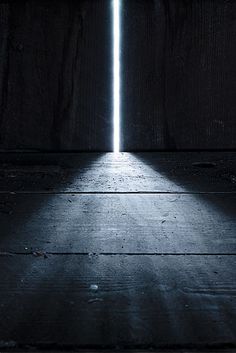 an open door in the dark with light coming from it and a bright beam at the end