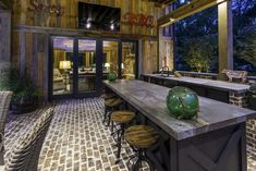 an outdoor bar with stools and tables in front of the doors that lead to another room