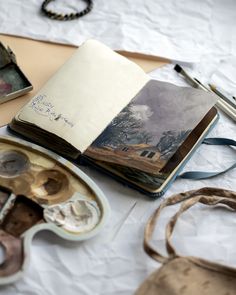 an open book sitting on top of a table next to other art supplies and tools