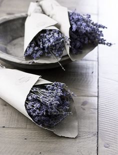 dried lavender flowers are wrapped in paper on a wooden table, ready to be eaten