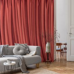 a living room with red drapes on the wall and a gray couch in front of it