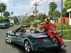 a man sitting on top of a sports car in the middle of a street with palm trees