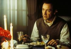 a man sitting at a table in front of a plate of food with candles on it