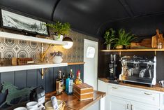 there is a coffee maker on the counter in this kitchen with white cabinets and black walls