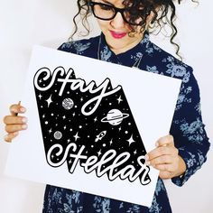 a woman holding up a sign that says stay off the earth with stars and planets