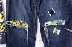 an old pair of jeans that has been torn and pinned together with some sewing tools