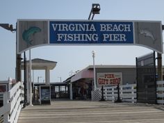 a pier with a sign that says virginia beach fishing pier on the front and side