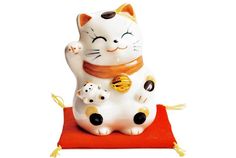 a white cat figurine sitting on top of a red mat