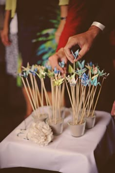 a table topped with small cups filled with cake pops and paper cranes on top of them