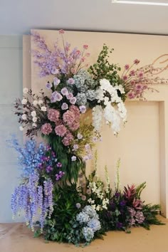 an arrangement of flowers is displayed in front of a fireplace