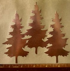 three metal trees are shown next to a ruler