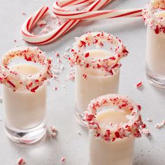 three glasses filled with white chocolate and candy canes next to peppermint sticks