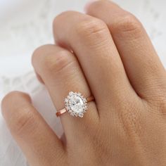 a woman's hand with a diamond ring on top of her finger and white lace in the background