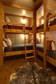 bunk beds are lined up in a room with wooden floors and walls, along with cowhide rugs on the floor