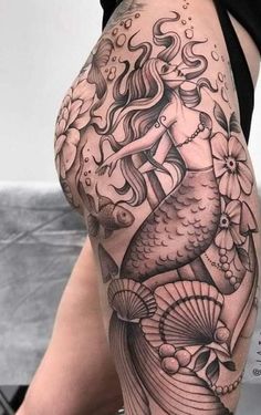 a woman's thigh with a tattoo design on her leg and an image of a mermaid