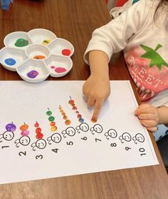 a young child is doing crafts on a sheet of paper with numbers and letters painted on it