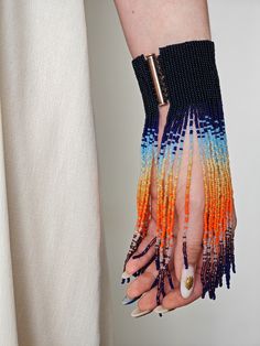 a woman's hand with multicolored beaded bracelets and ring on it