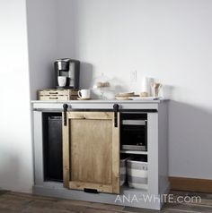 a kitchen cabinet with an open door on the top and bottom, in front of a white wall