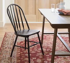 a wooden chair sitting on top of a red rug next to a table and chairs