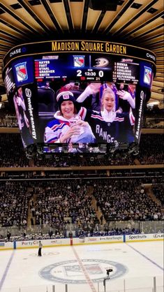 an ice hockey stadium filled with people watching the game on large screen tvs and fans