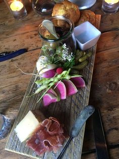 a wooden table topped with different types of food and utensils next to candles