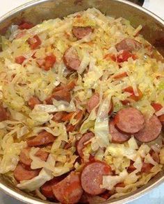 a pan filled with sausages and cabbage on top of a stove next to an oven