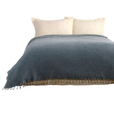 a blue and white bed with two pillows on it's headboard, next to a pillow that has fringe trim around the edges